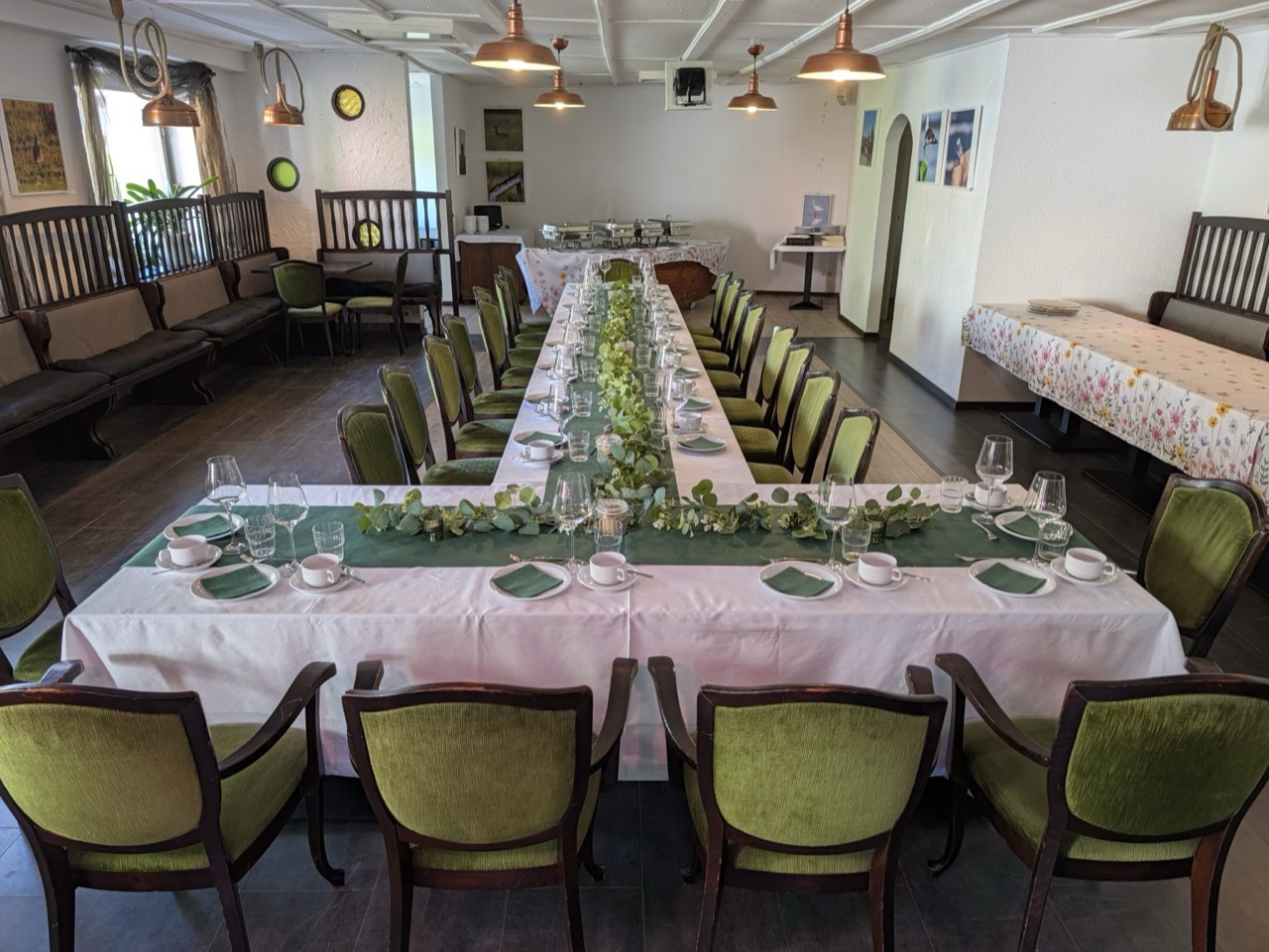Der Saal festlich eingedeckt: lange Tafel mit weißen Tischdecken und grünem Läufer